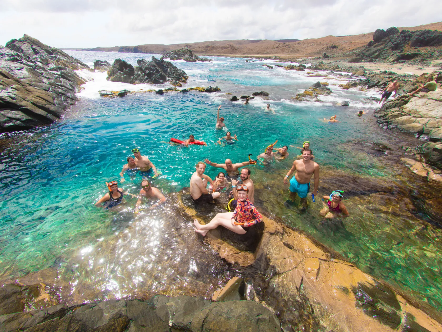 a group of people sitting on a rock next to a body of water