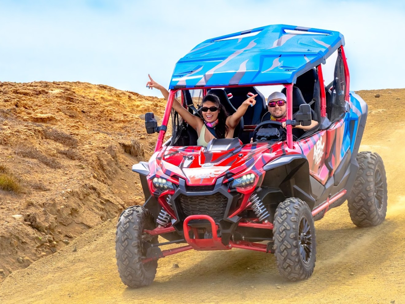 Two people in an off-road vehicle driving on a dirt path.