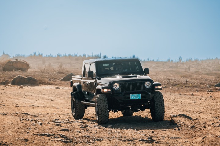 Black off-road vehicle on a dusty, rugged landscape under a clear blue sky.