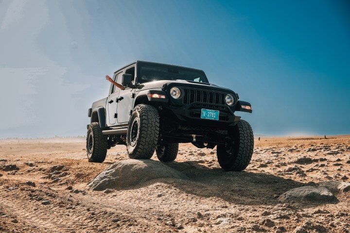 Black off-road vehicle on rocks in desert landscape under clear blue sky.