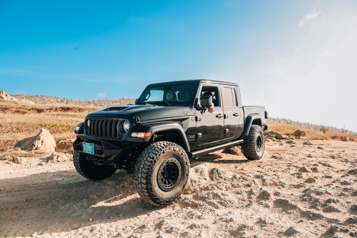 Black off-road vehicle on a rocky, desert terrain under a clear blue sky.