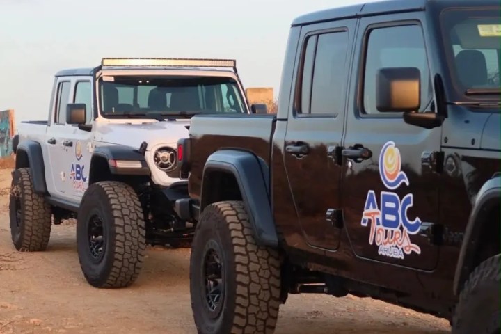 Two jeeps with 'ABC Tours' logos parked on a dirt road.