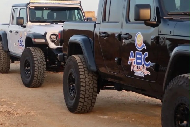 Two off-road vehicles on a dirt path with tour logos.