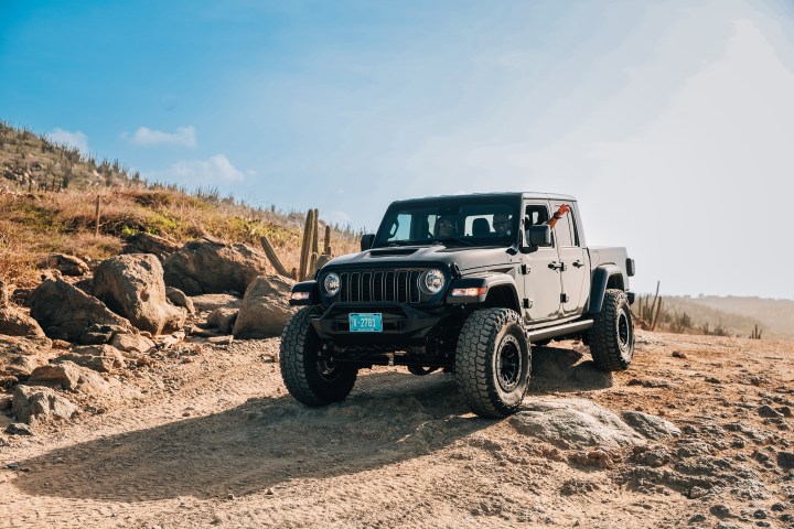 Black off-road vehicle on rocky terrain under clear blue sky.
