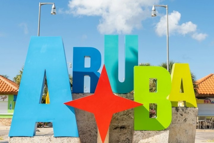 Colorful 'Aruba' sign with a star, under a blue sky.